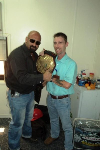 Holding a championship wrestling belt with Ali Farhat.
