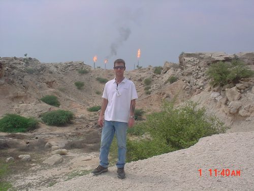 Standing on a ridge with gas flares burning behind.