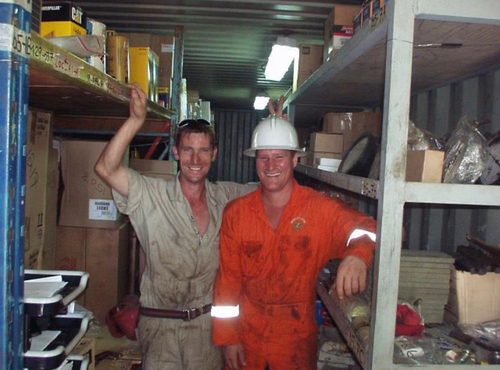 Two men in coveralls in a stores container.