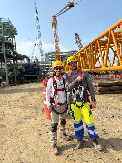 Two technicians in climbing harnesses on a construction site.