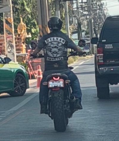 A rider in club colours on a motorcycle in traffic.