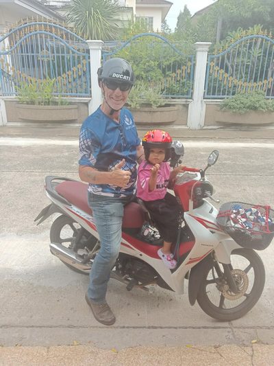 A man and a small child on a Honda Wave outside a house.
